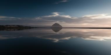 distant mountain with reflection on calm Water at dusk