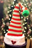 Beautiful and colorful, cute figure of the elf in striped hat, near the Christmas tree with lights