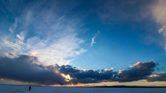 Man walks on snowy frozen lake at Sunset