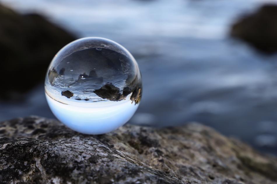 glass ball on the sea coast close up on blurred background