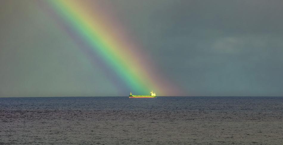 Beautiful waterscape of the sea with ship, at colorful and beautiful rainbow