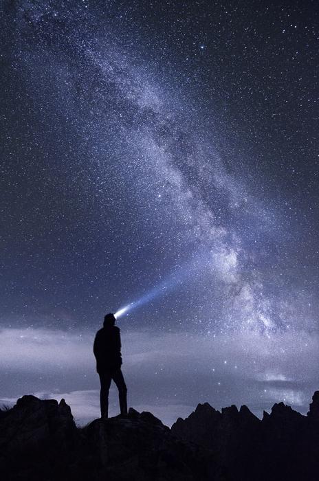 guy with a flashlight under the starry sky