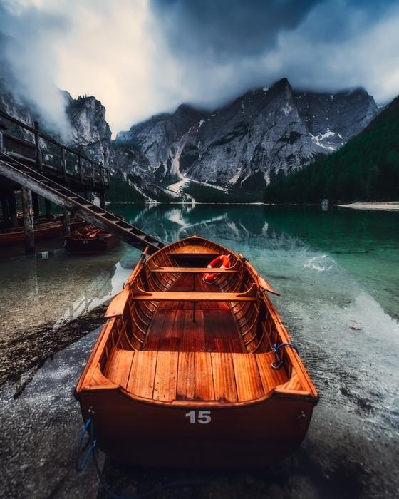 Beautiful, wooden boat near the lake, and mountains in Italy, under the clouds