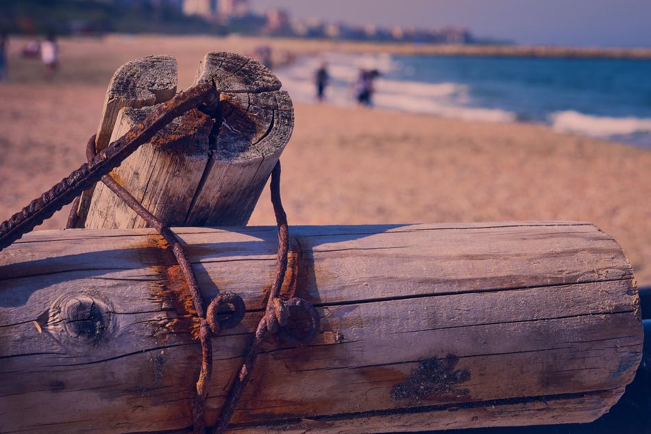 Old, rusty, wooden and metal construction on the sandy beach with waves