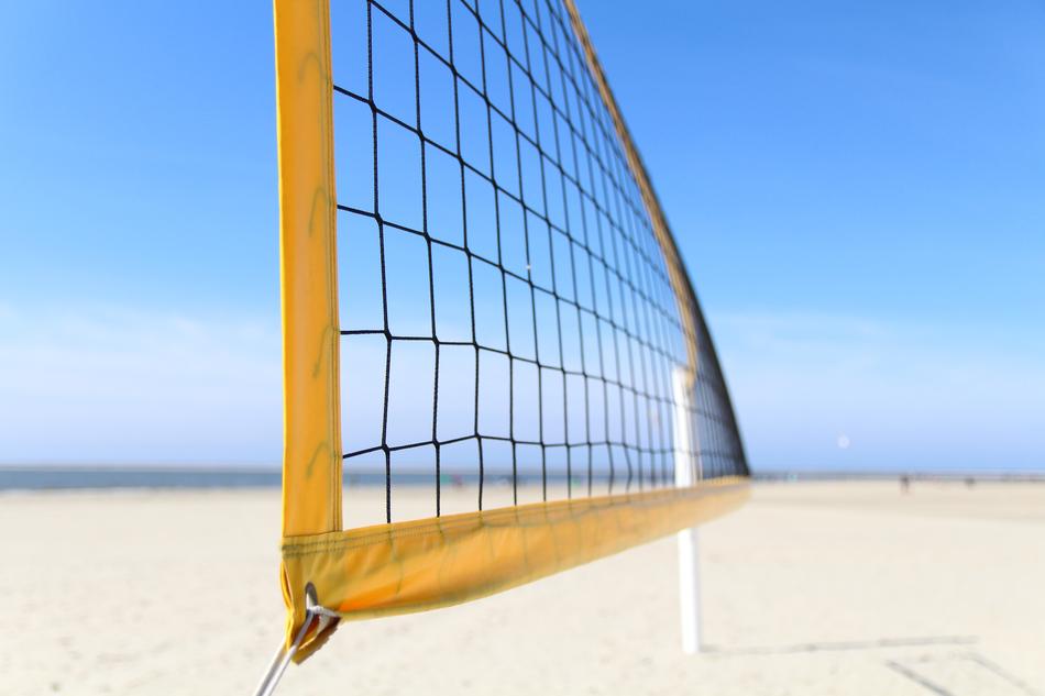 Yellow volleyball net on the sandy beach in sunlight, under the blue sky