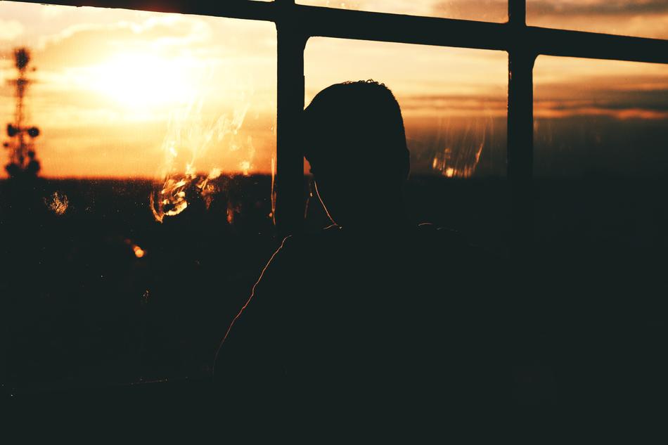 Silhouette of the man, near the windows, with the view of colorful and beautiful sunset