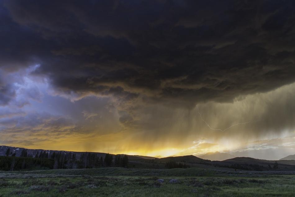 Thunderstorm over meadow and hills at Sunset