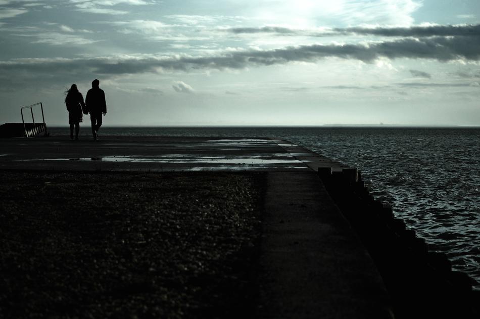 couple holding hands on the pier at night