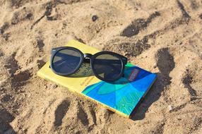 sunglasses and book on sand