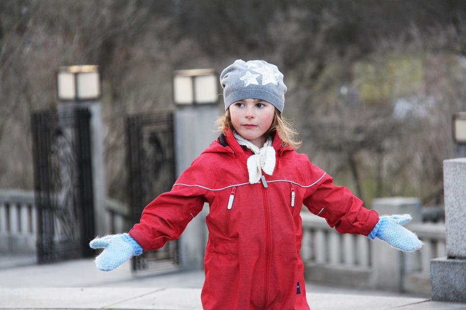 funny child girl in winter clothing with wide open hands outdoor, norway, oslo
