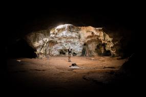 girl at cave opening among rocks