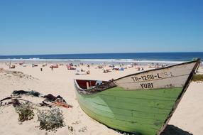 Green boat against the background of holidaymakers on the beach