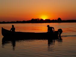 silhouette of a boat with people on the lake