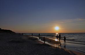silhouettes of people walking on the beach
