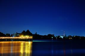 illuminated pier Reflection on Blue water at night