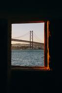 Window with a view of the ocean with a bridge