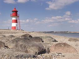 A red lighthouse on a rocky beach
