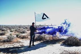 man holds white flag near Blue Smoke