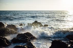 The waves crash against the rocks of the sea