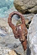 Old Rusty mooring loop on rock at water