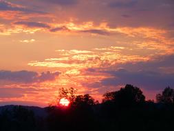 sun setting in colorful sky over countryside