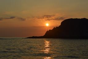 the sun hiding behind the mountain