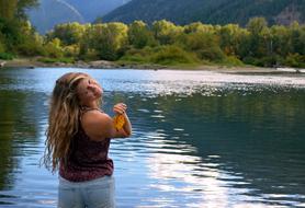 happy woman with leaf in hand standing in water