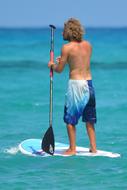 Man with Paddle standing on surfboard