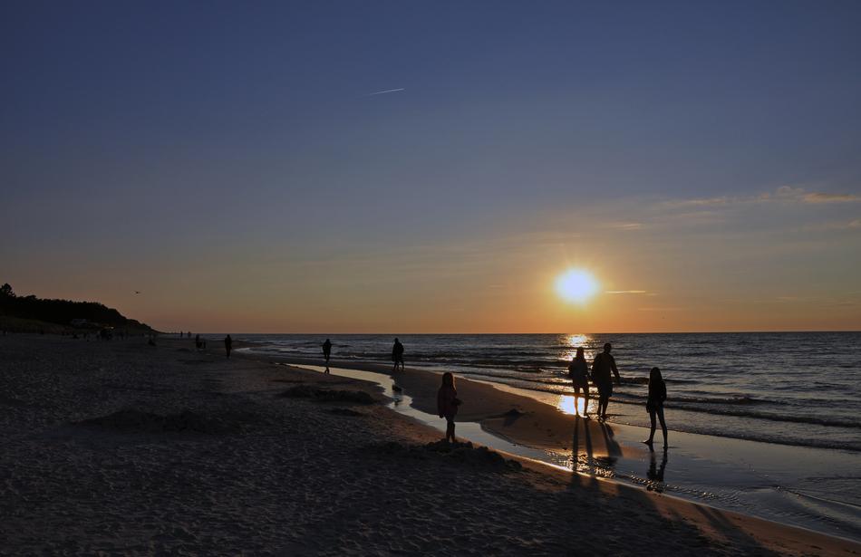 silhouettes of people walking on the beach