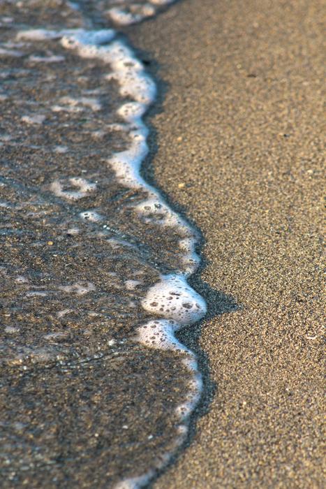 Foamy sea wave on a sandy beach