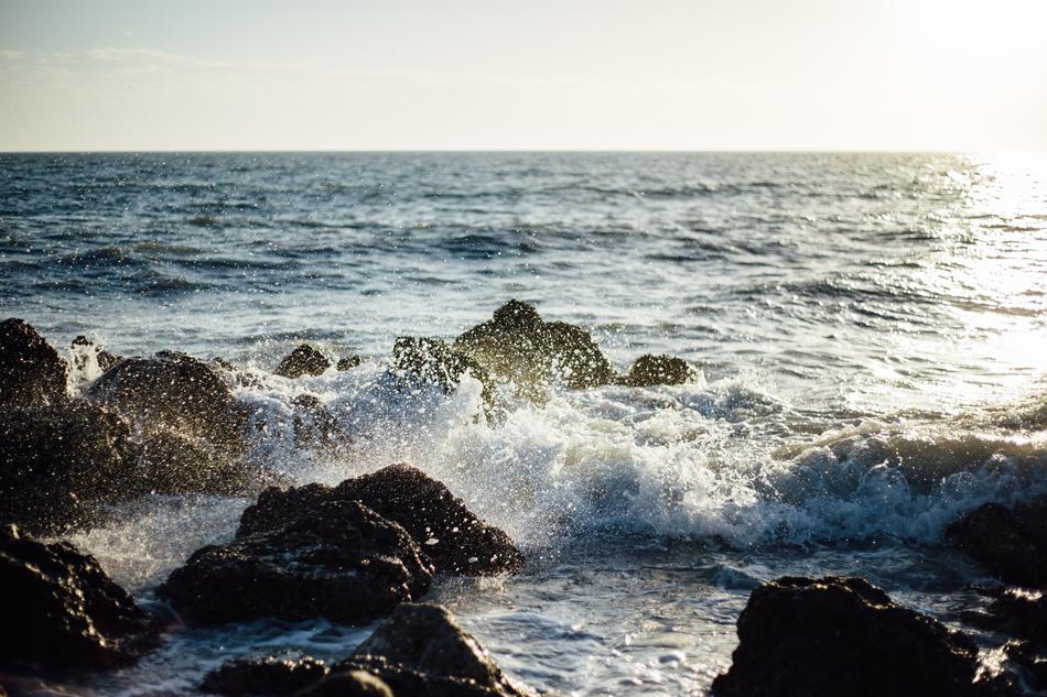 The waves crash against the rocks of the sea