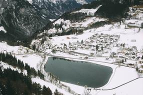 village near lake in mountain valley on snowy winter