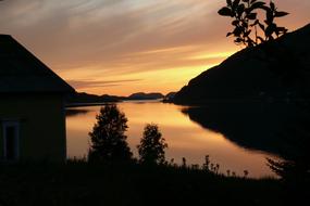 the black silhouette of a mountain by the lake