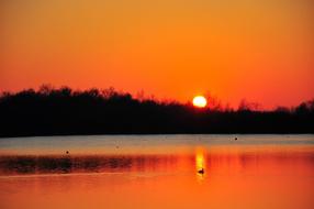 the silhouette of the mountains with the sun in the lake