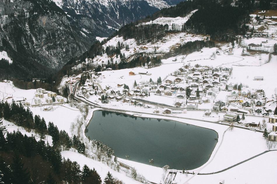 village near lake in mountain valley on snowy winter