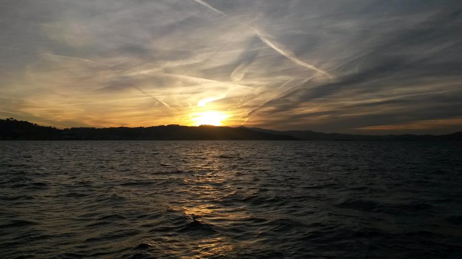 golden cirrus clouds in evening sky over dark water