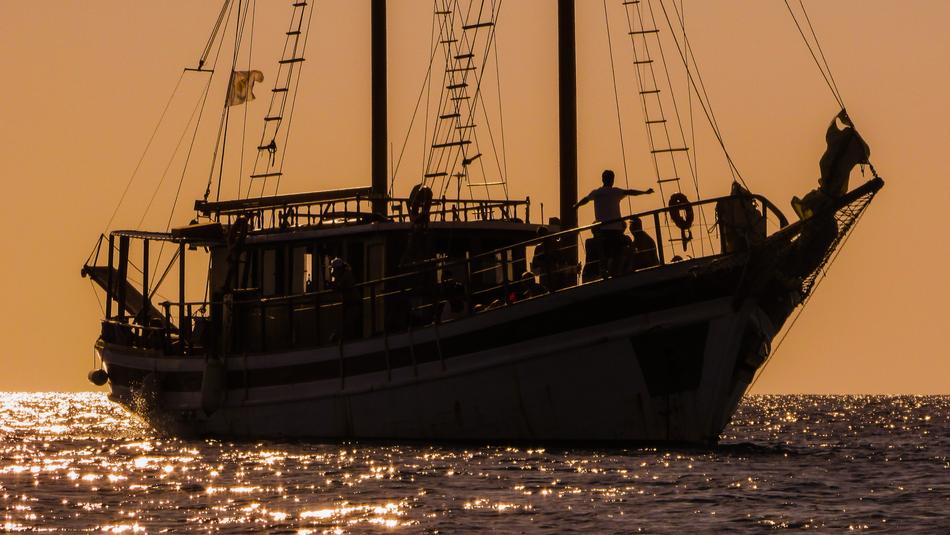 people on Sailboat in Sea at Sunset