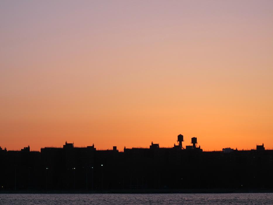 A silhouette of the city against an orange sky