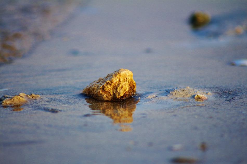 a small rock in the sand in the sea