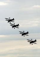 Four flying biplanes in the beautiful sky with clouds