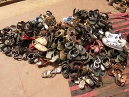a pile of sandals at the entrance to the mosque