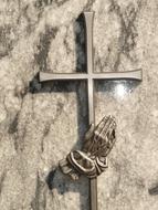 metal cross and hand on a tombstone
