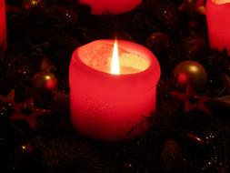 burning red wax candle in advent wreath