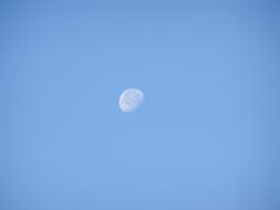 white moon on a clear blue sky