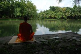 Buddhist monk meditating at water