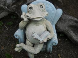 decorative ceramic frog on a chair in the garden