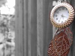 necklace with a clock and gold leaves on the fence