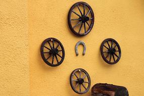 wooden cart wheels and horseshoe on a yellow wall