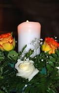 white candle near artificial flowers