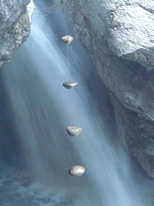 Stones hanging on rope in front of Waterfall